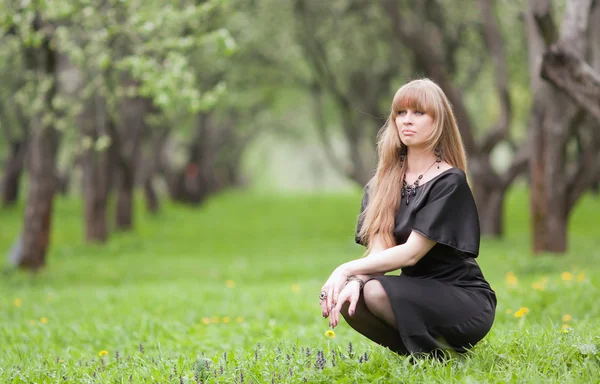 Das Mädchen auf einem Gras sitzend — Stockfoto