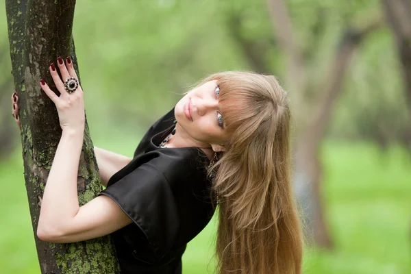 女性は木の幹に肘を突いた — ストック写真