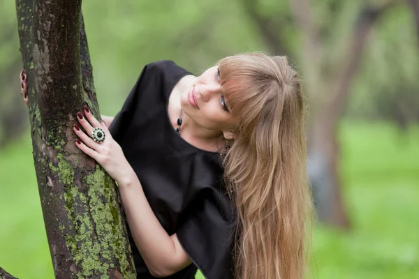 De mooie vrouw leunde de ellebogen op een boom — Stockfoto