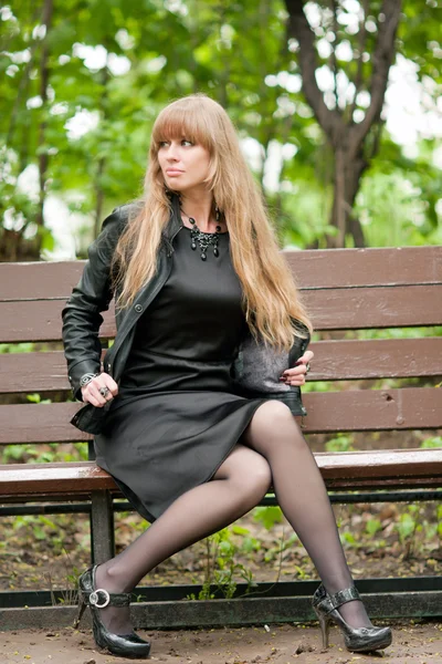 Das Mädchen auf einer Bank sitzend — Stockfoto