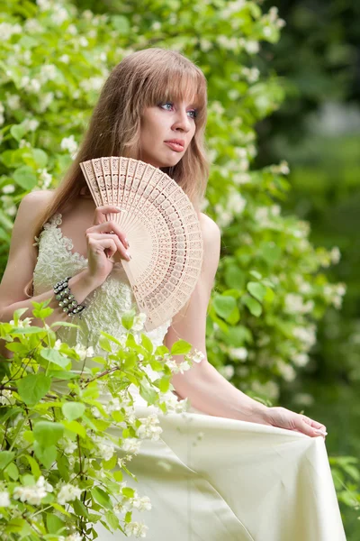 Het meisje met een ventilator in een witte jurk — Stockfoto