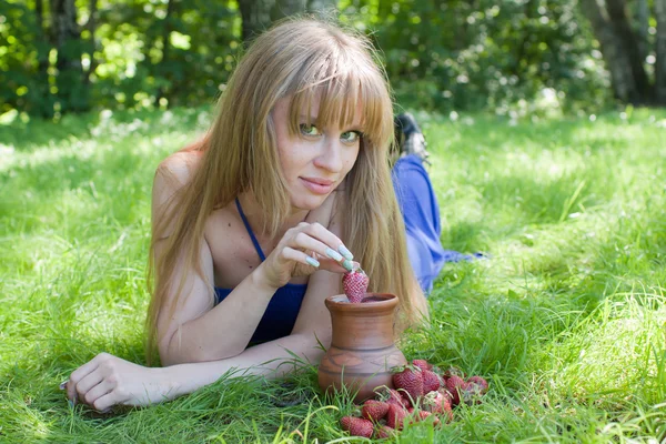 A mulher em uma grama e um morango com o leite — Fotografia de Stock