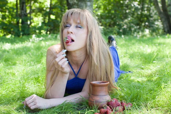 A mulher em uma grama também gosta de um morango — Fotografia de Stock