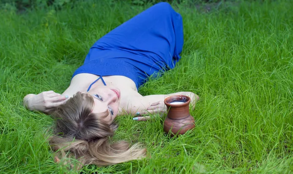 A mulher em uma grama e um jarro de leite — Fotografia de Stock