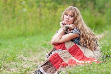 The thinking girl sits on a grass