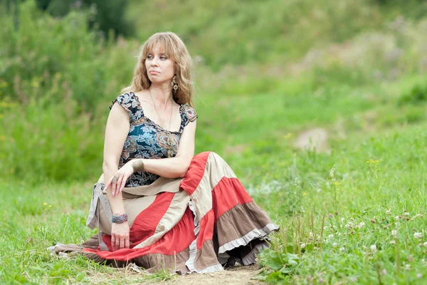 Hipis kobieta siedzi na trawie — Zdjęcie stockowe