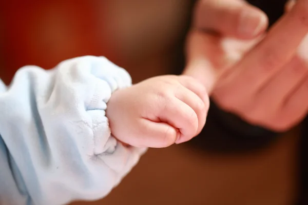 Baby holding mother's finger — Stock Photo, Image