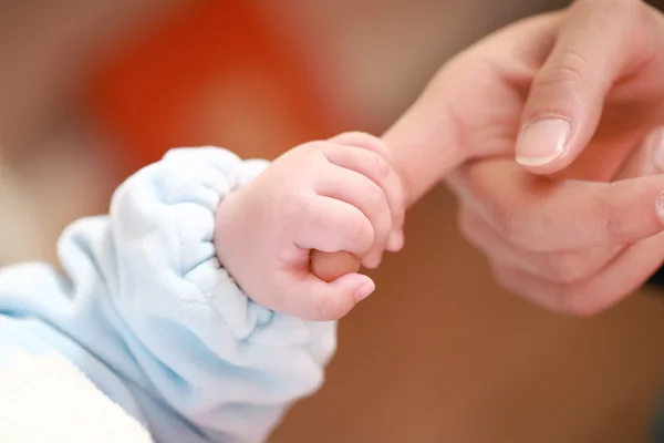 Baby holding mother's finger — Stock Photo, Image