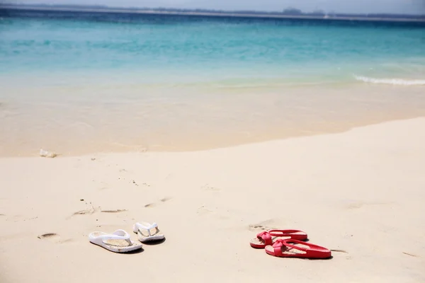 Rote und weiße Hausschuhe am Strand — Stockfoto