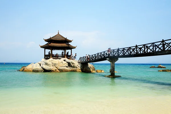 Uma ponte de madeira que leva a um pavilhão de madeira sobre o mar — Fotografia de Stock