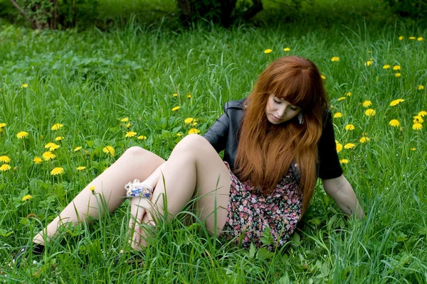 Девушка, сидящая на поле одуванчиков — стоковое фото