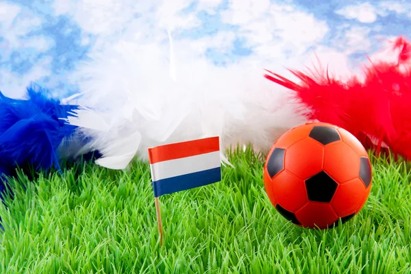 Bola de futebol laranja e bandeira holandesa na grama — Fotografia de Stock