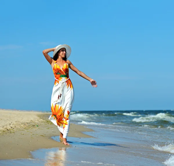 Een vrouw die over het strand loopt — Stockfoto