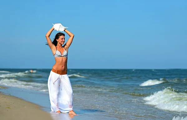 Een vrouw die over het strand loopt — Stockfoto