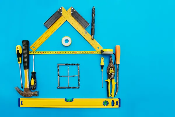 Strumenti a forma di casa su sfondo blu. Miglioramento domestico — Foto Stock