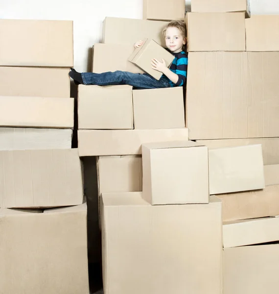 Chico está sentado en cajas de cartón — Foto de Stock