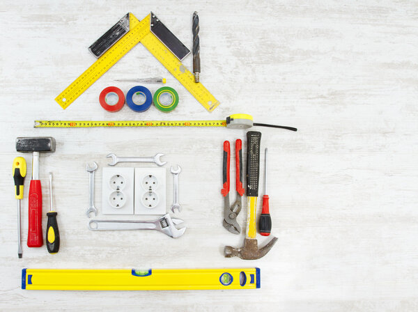 Tools in the shape of house over wooden background. Home improving, repair concept.