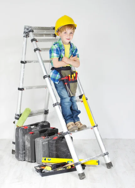 Pequeno menino faz-tudo com capacete e cinto de ferramentas na escada rolante — Fotografia de Stock