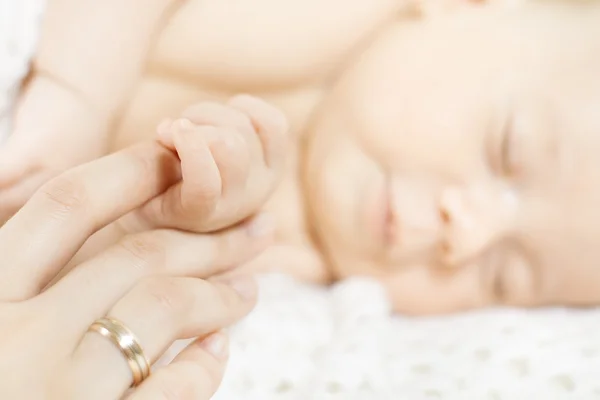 生まれたばかりの赤ちゃんの手が親の指を保持します。クローズ アップ. — ストック写真