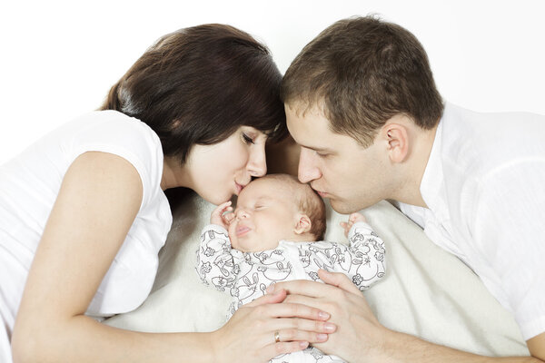 Parents kissing sleeping newborn baby over white background. Family love concept.