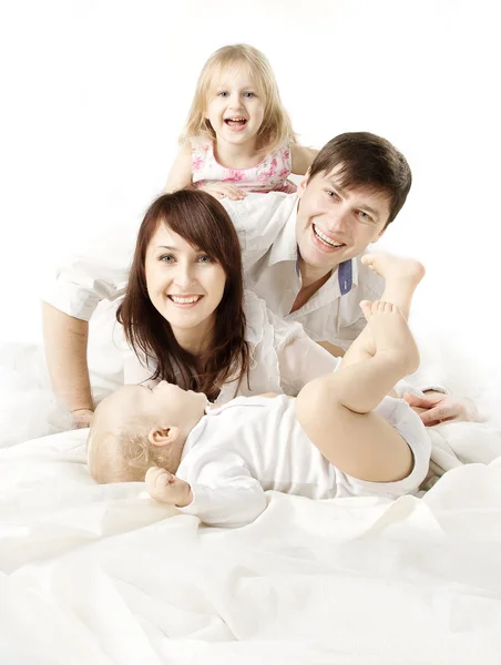Familia feliz: padres jugando con dos niños en la cama. Mirando c —  Fotos de Stock