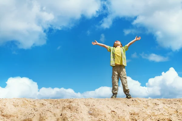 Happy child standing with hands raised up over blue sky — Stock Photo, Image