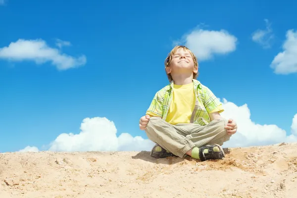 Gelukkig kind positief denken, jongen zitten in Yoga lotuspositie over blauwe hemel op de top. Kid geluk en vrijheid concept. — Stockfoto