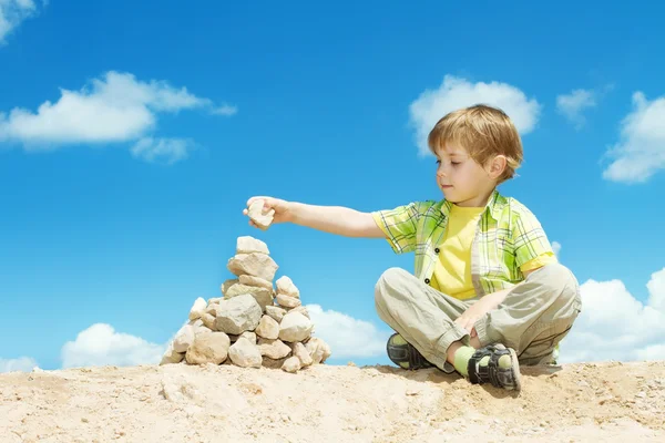 Çocuk son bir taş parçası için tam piramit koyarak — Stok fotoğraf
