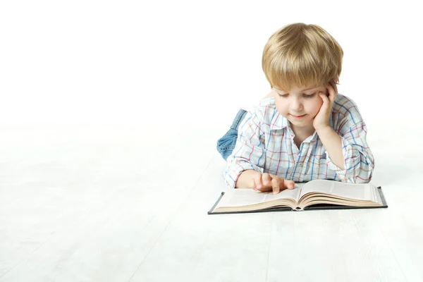 Ребенок читает книгу, мальчик читает в школе, лежа на белом полу — стоковое фото