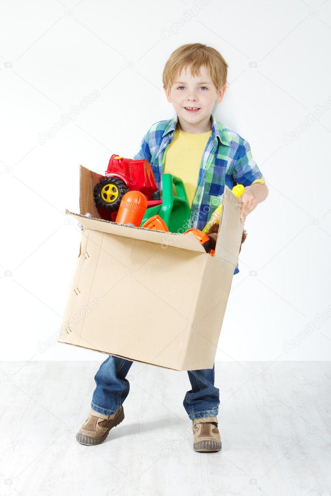 Child holding cardboard box packed with toys. Moving and growing