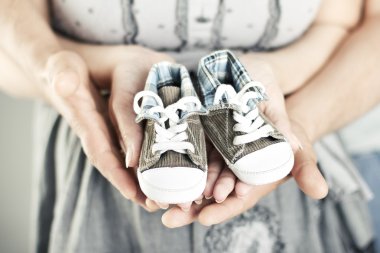 Newborn baby booties in parents hands clipart