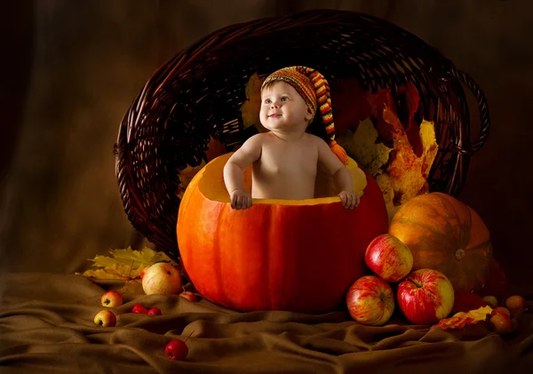 Child in cap inside pumpkin. Basket with autumn harvest — Stock Photo, Image