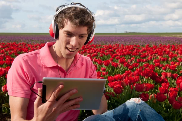 Junger Mann mit alter Fotokamera im Feld mit Tulpen — Stockfoto