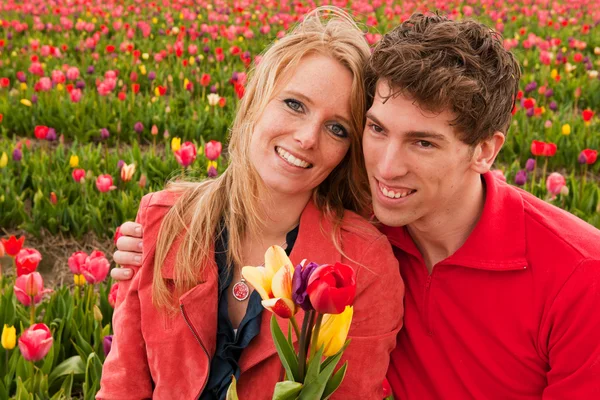 Unga kärlekspar i nederländska blomma fält — Stockfoto