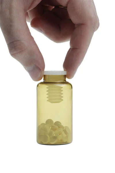 Botella pequeña con píldoras sostenidas por la mano del hombre — Foto de Stock