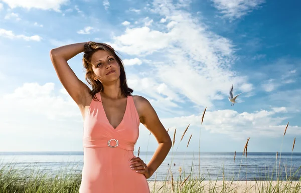 Sahil üzerinde pembe elbiseli kadın — Stok fotoğraf
