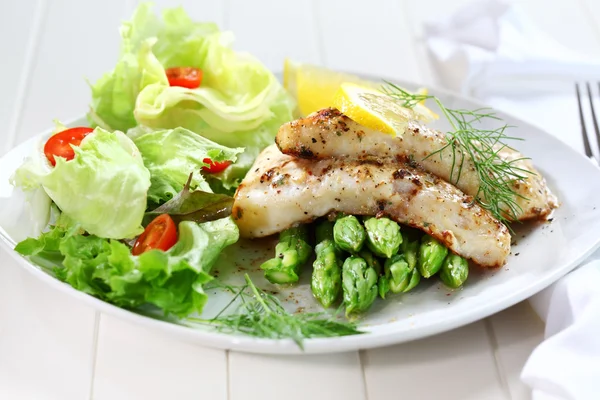 Fried fish on green asparagus with salad — Stock Photo, Image