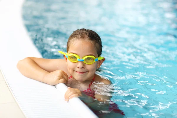 Schoolgirl with goggles in swimming pool — Stock Photo, Image