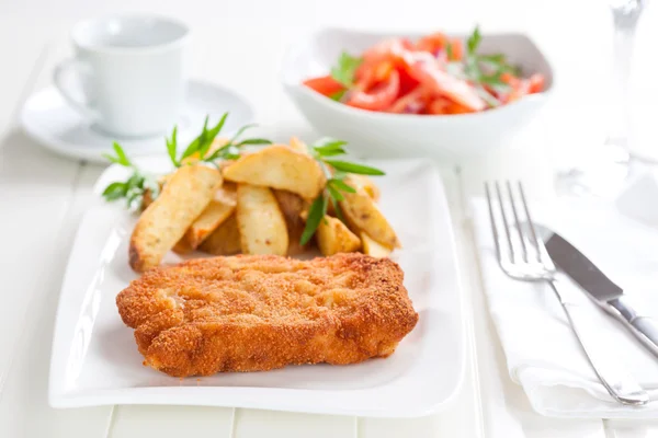 Schnitzel with wedges and tomato salad — Stock Photo, Image