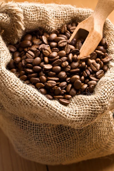 Coffee beans in canvas sack with wooden scoop — Stock Photo, Image