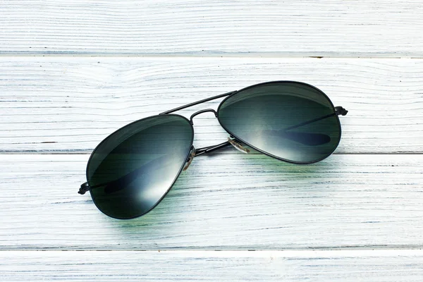 Óculos de sol no chão de madeira branca — Fotografia de Stock