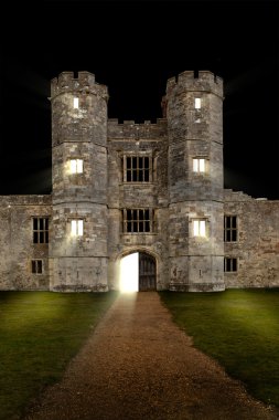 Old castle at night with lights shining through windows clipart
