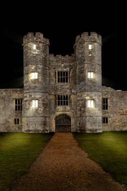 Old castle at night with lights shining through windows clipart