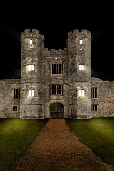 Old castle at night with lights shining through windows — Stock Photo, Image