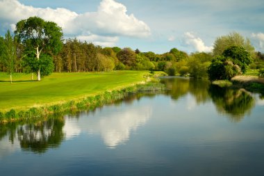 Idyllic golf course at the river clipart