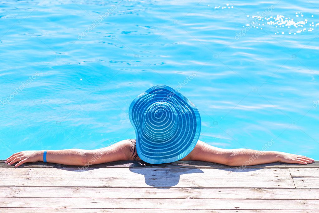 Woman in hat relaxing at swimming poo