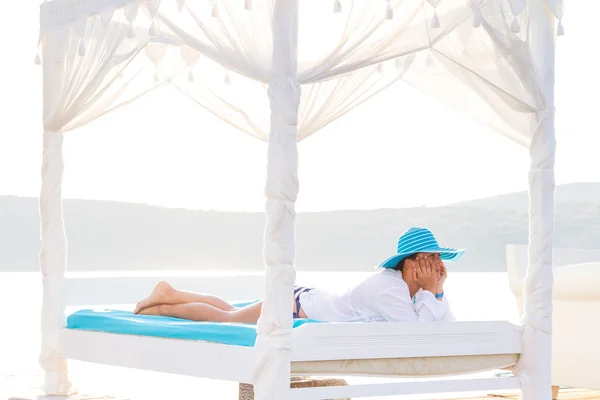 Lüks beyaz yatak üzerinde rahatlatıcı şapkalı kadın — Stok fotoğraf