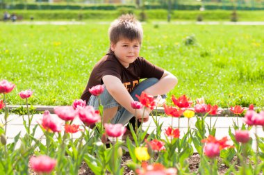 Lale ile flowerbed oturan çocuk