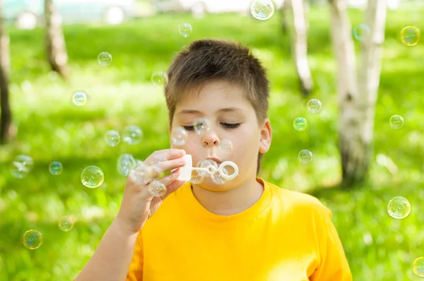 O menino sopra bolhas no parque — Fotografia de Stock