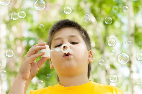 Мальчик надувает пузыри в парке — стоковое фото